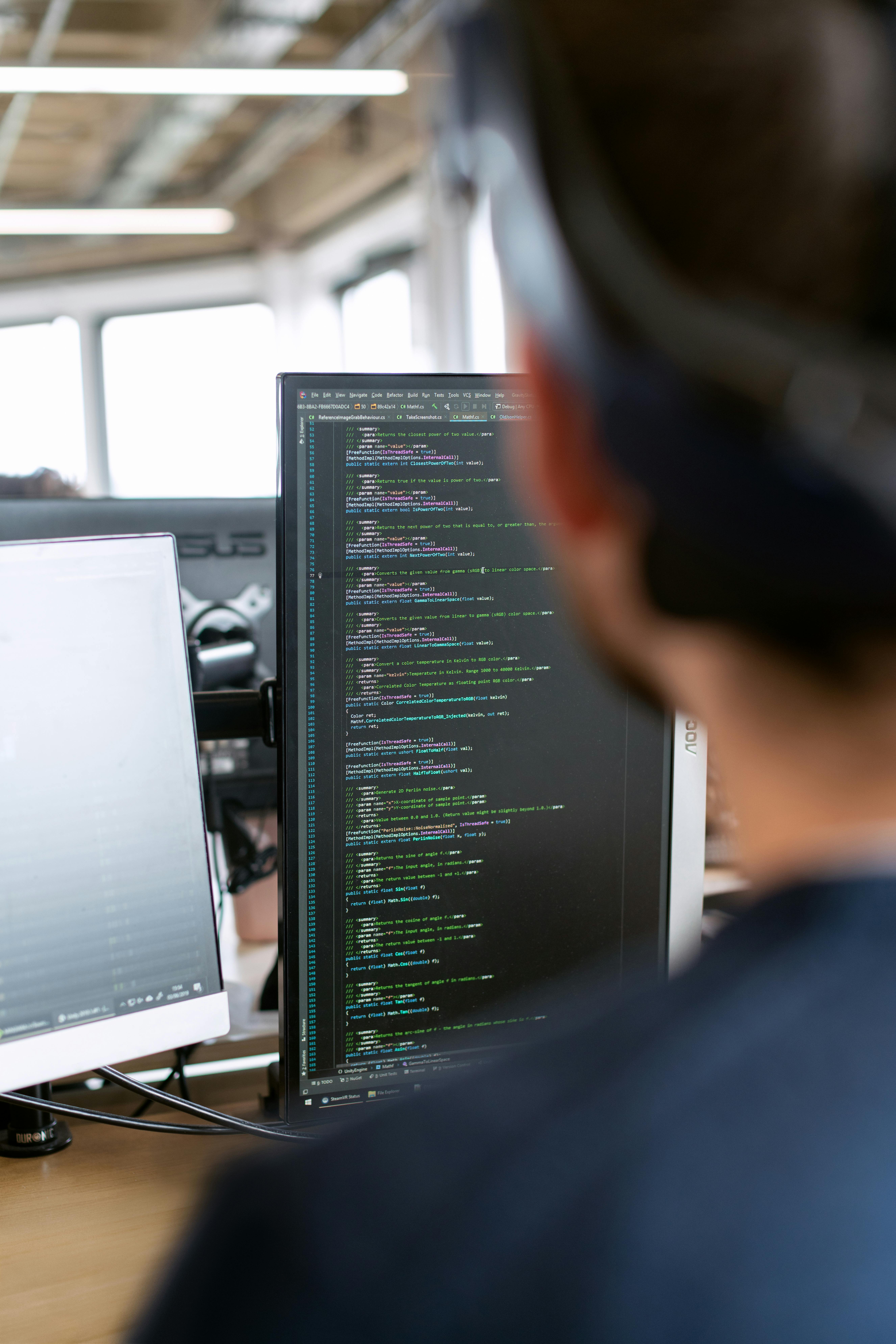 A focused website developer typing code on a laptop, working on the design and functionality of a custom website for a client.